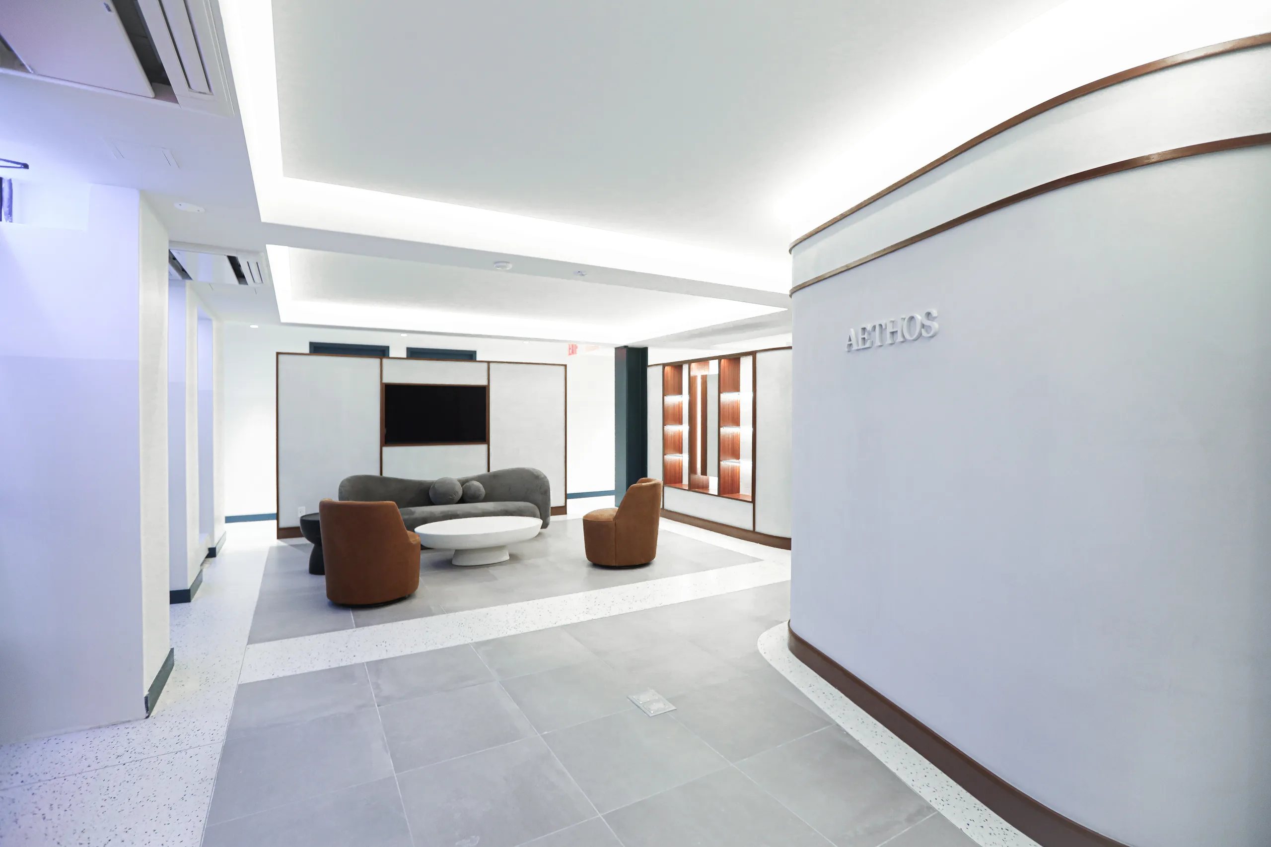 AETHOS reception lounge with curved seating and illuminated millwork