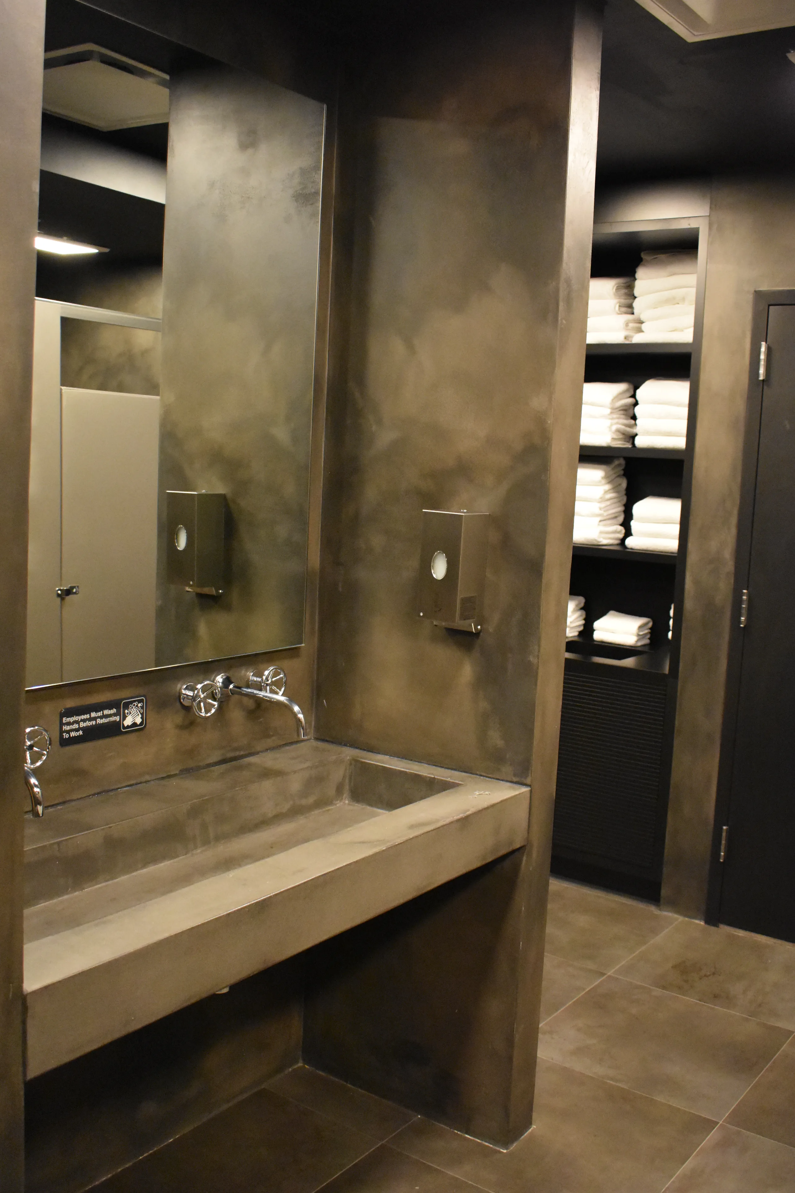 Goal Mine Health Club locker area with dark concrete sink and towel shelving